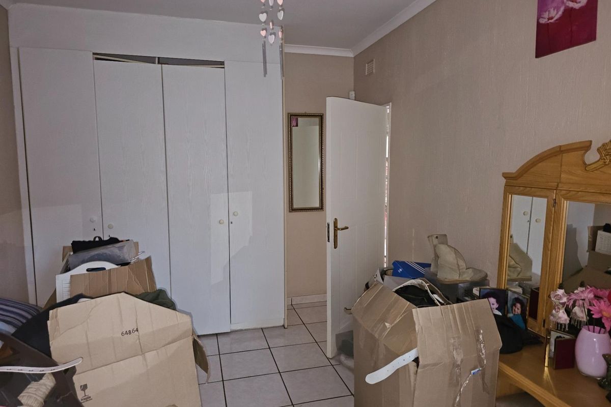 A bedroom featuring tiled flooring and built-in cupboards, providing functional storage space.