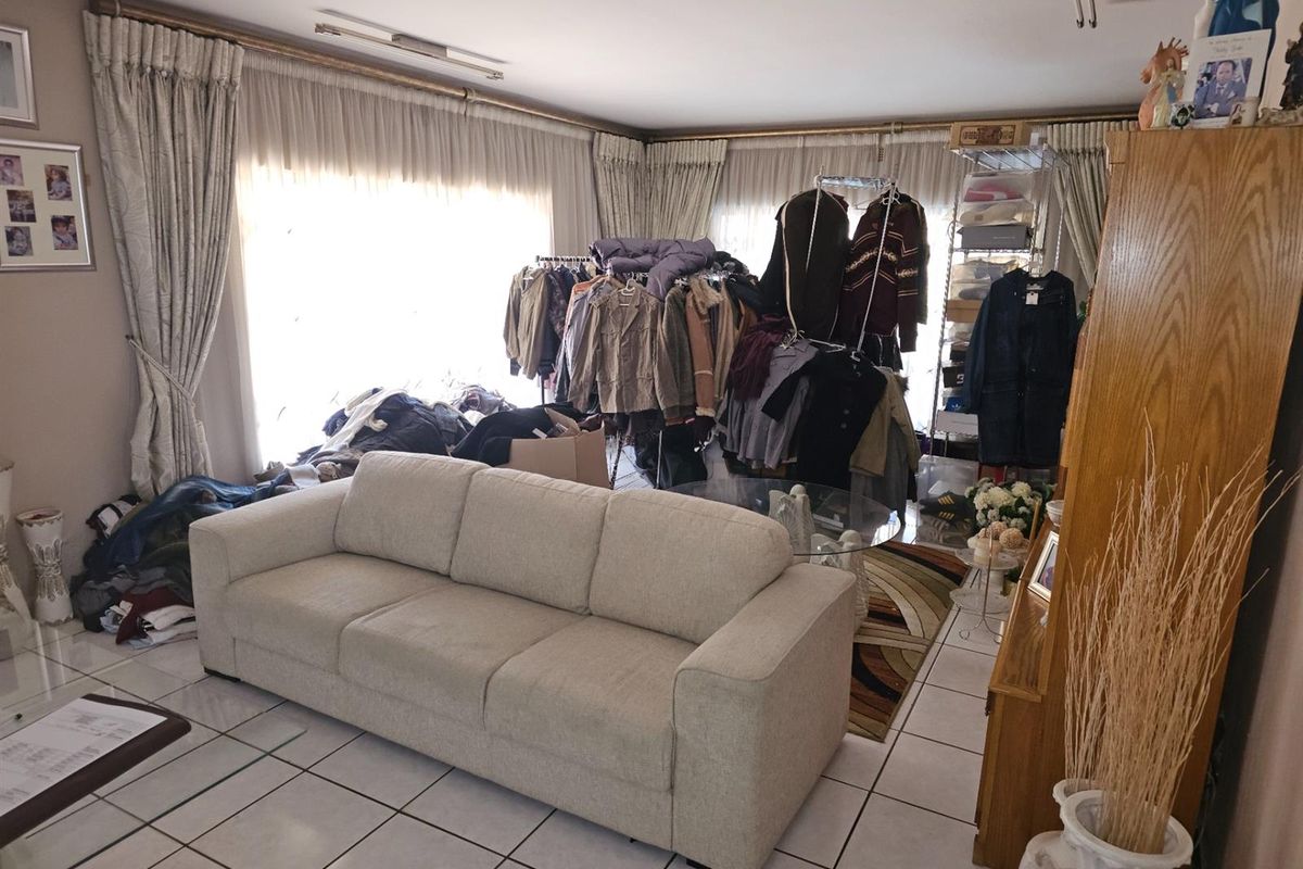 Spacious living room featuring ceramic floor tiles and large windows with curtain tracks, offering a bright and versatile living area.