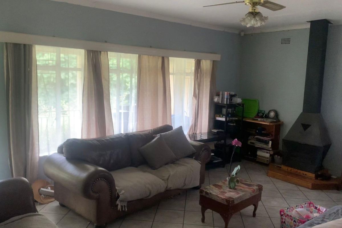 A living room featuring a built-in metal fireplace, tiled flooring, and large windows with natural light.