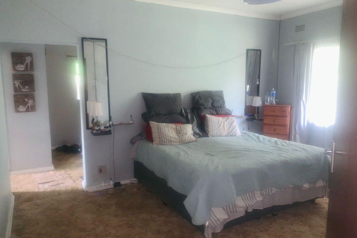 A bedroom featuring carpeted flooring, a window with curtains, and a doorway leading to an adjacent space.