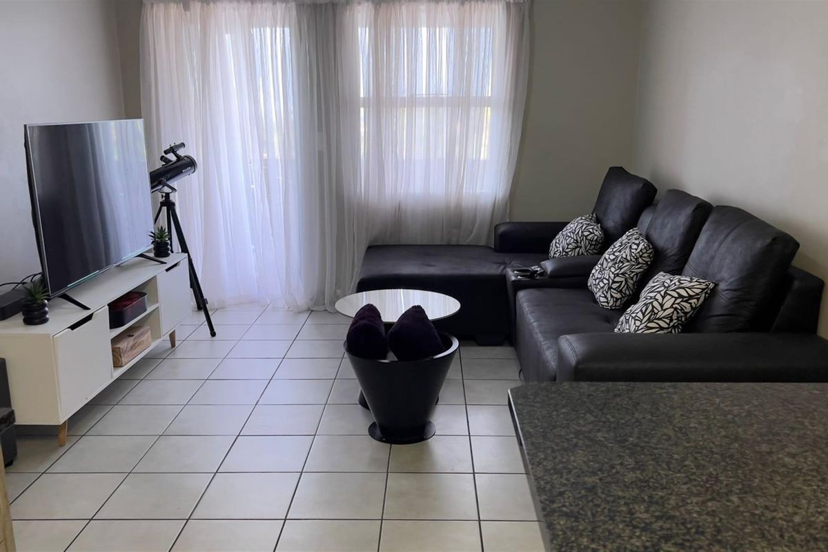 A comfortable living room featuring tiled flooring and large sliding glass doors that provide access to an outdoor area.