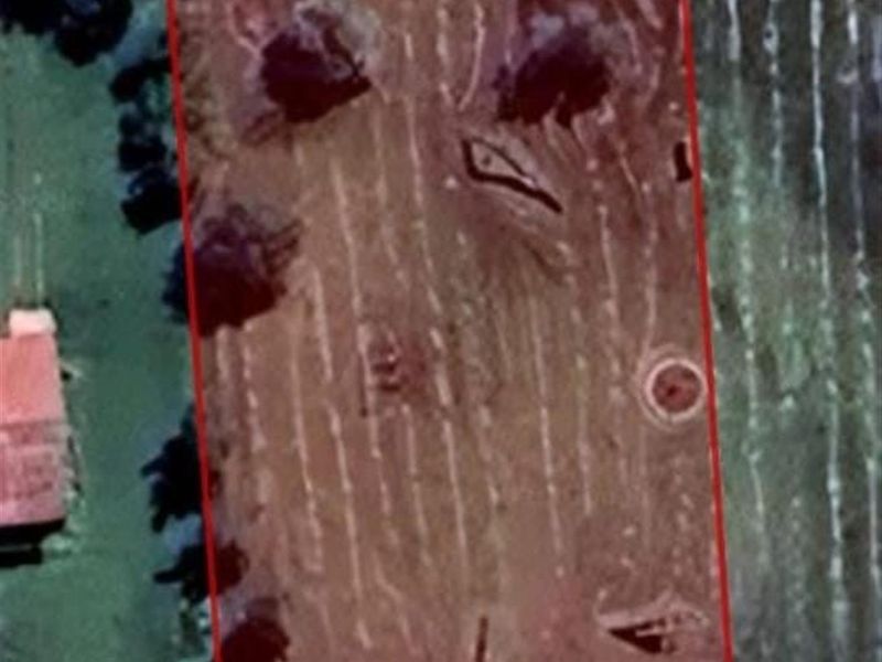 An aerial view of a vacant residential plot of land with clear boundary lines indicated.