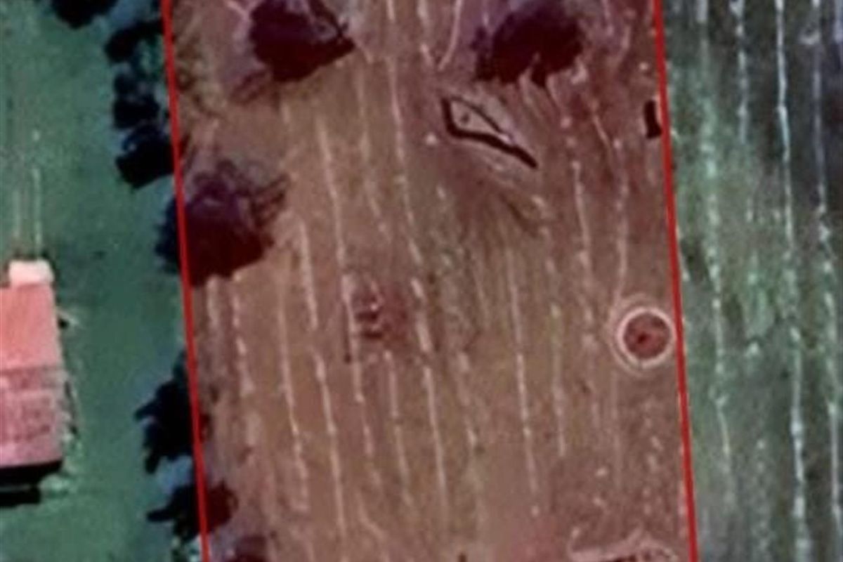 An aerial view of a vacant residential plot of land with clear boundary lines indicated.