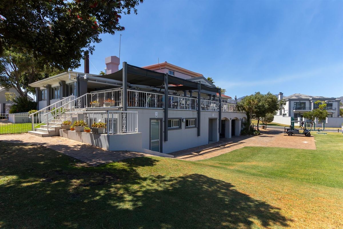 Rear exterior view of the property featuring a raised patio deck with metal railings, covered pergola, and paved ground level access.