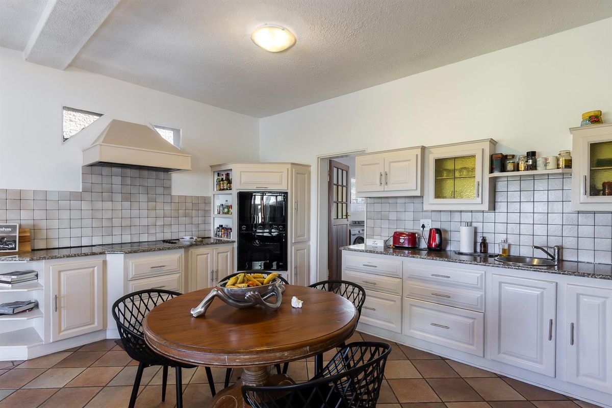 A functional kitchen featuring light-toned cabinetry, granite countertops, tiled splashbacks, and a built-in oven with an extractor fan.