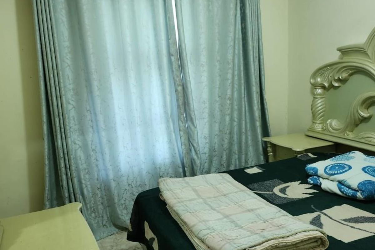 A bedroom featuring tiled flooring, a built-in ventilation vent, and curtain tracks installed above the window.