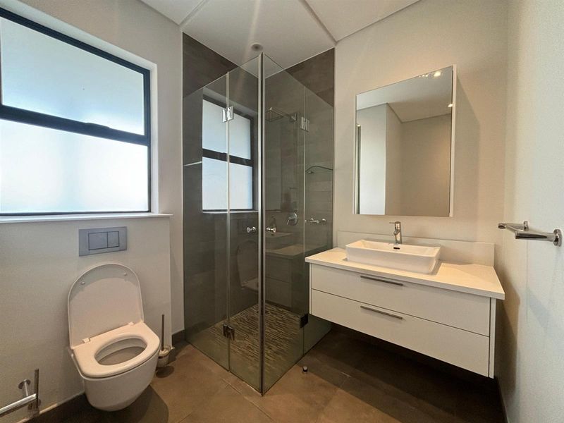 Modern bathroom featuring a floating vanity with vessel sink, glass-enclosed shower with rain head, and a wall-hung toilet with concealed cistern.