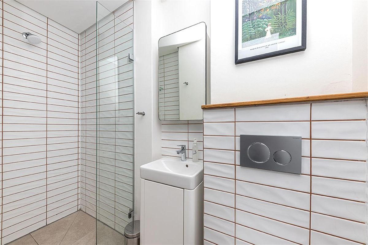 Modern bathroom featuring a walk-in shower with glass screen, wall-mounted vanity basin, and concealed cistern toilet with dual-flush plate.