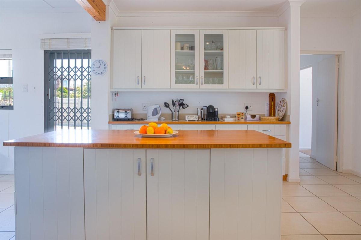 A bright kitchen featuring white cabinetry, a wooden island countertop, and tiled flooring, offering a clean and functional workspace.