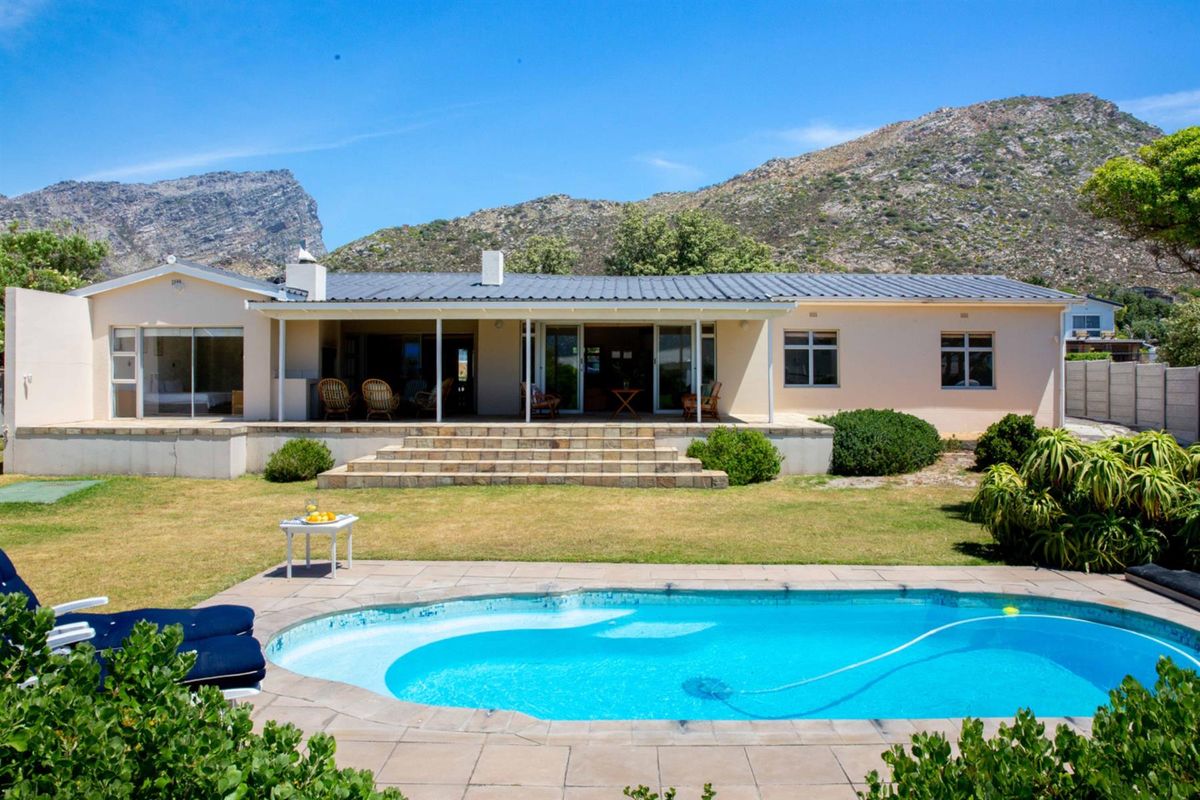 Rear view of the house featuring a swimming pool, paved patio area, and covered veranda with mountain views.