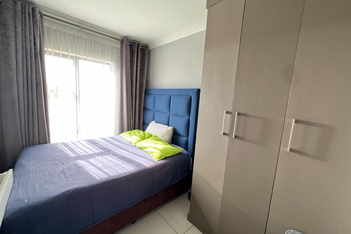 A well-maintained bedroom featuring built-in cupboards, tiled flooring, and sliding glass doors providing natural light.