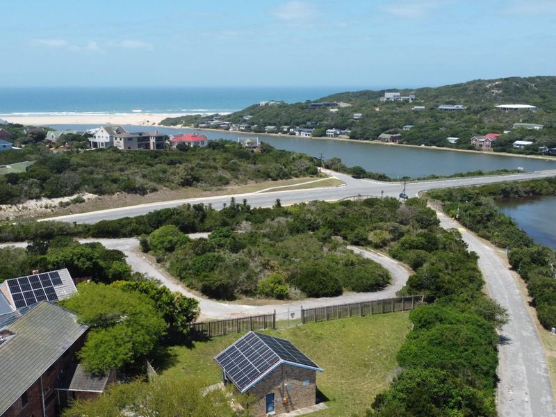 Aerial view of a residential plot featuring established vegetation, a small structure with solar panels, and proximity to the river and coastline.
