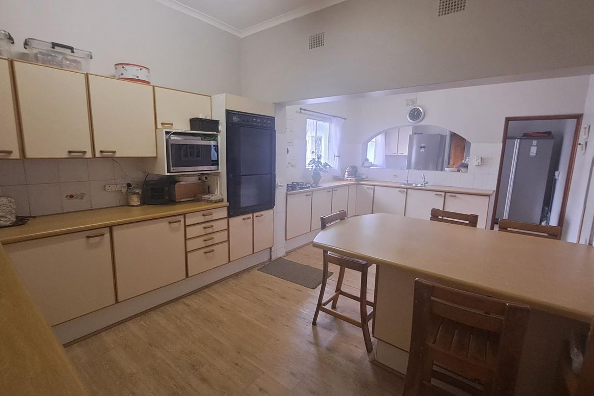 A spacious kitchen featuring laminate cabinetry, built-in oven, and a central breakfast bar, offering a functional layout with potential for modern updates.