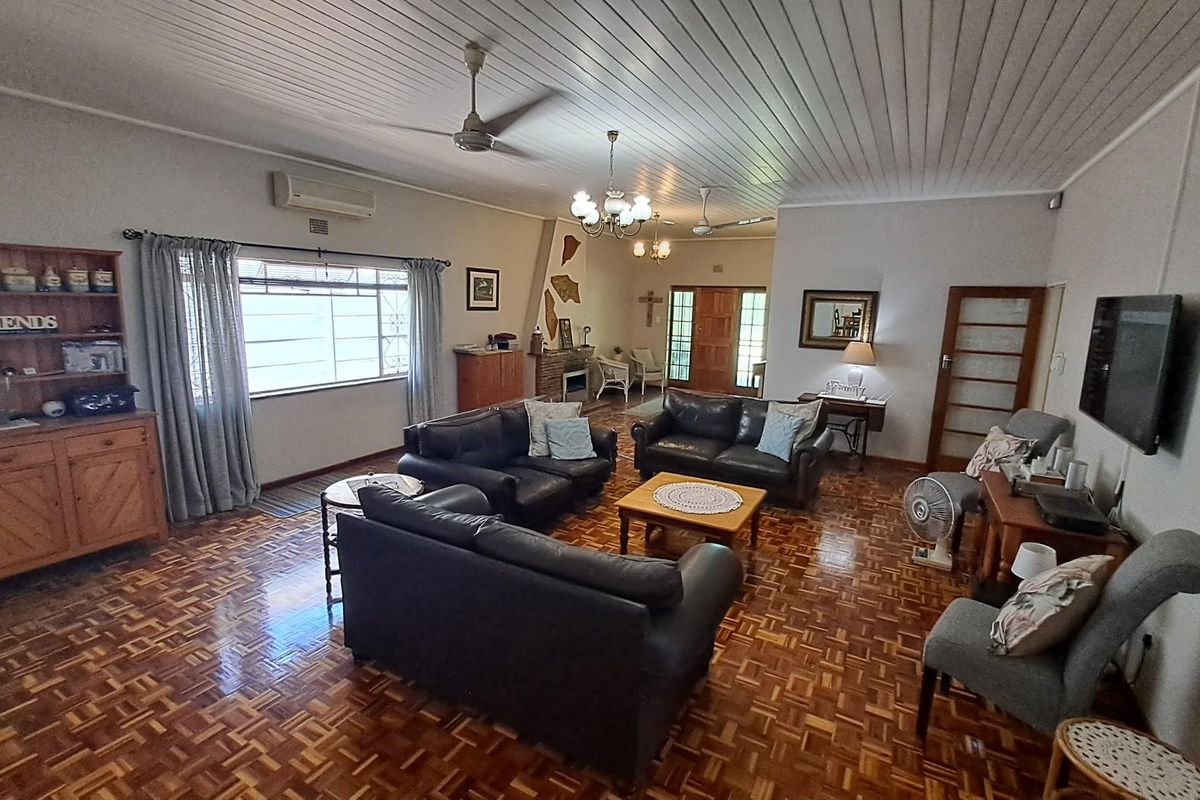Spacious living room featuring traditional parquet flooring, a built-in fireplace, and a ceiling fan, offering a comfortable and classic living environment.