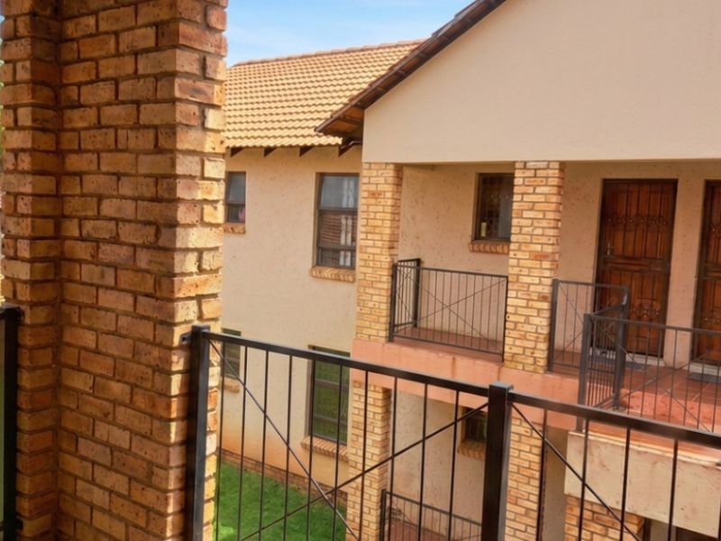 Exterior view of an apartment complex featuring face brick pillars, metal balustrades, and tiled balconies.