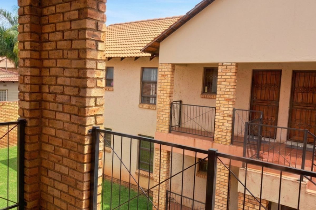 Exterior view of an apartment complex featuring face brick pillars, metal balustrades, and tiled balconies.