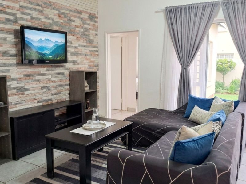 A comfortable living room featuring a decorative stone veneer accent wall, tiled flooring, and direct access to an outdoor patio area.