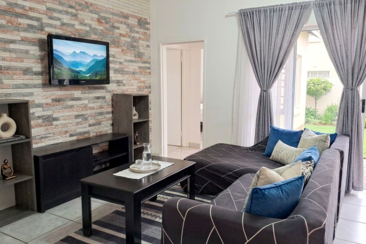 A comfortable living room featuring a decorative stone veneer accent wall, tiled flooring, and direct access to an outdoor patio area.