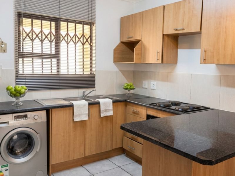 Functional kitchen featuring laminate cabinetry, granite countertops, an electric hob, and tiled flooring, with a built-in space for a washing machine.
