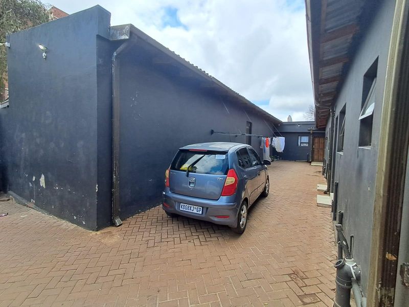 Rear exterior area featuring a paved driveway and dark-painted exterior walls with visible signs of wear and paint deterioration.