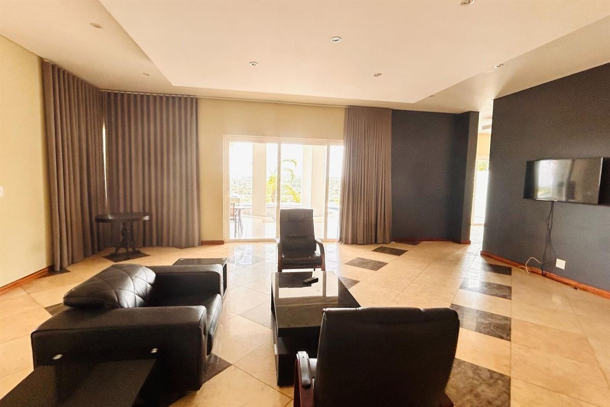 Spacious living room featuring tiled flooring with decorative inlays, recessed ceiling lighting, and large sliding glass doors leading to an outdoor patio area.