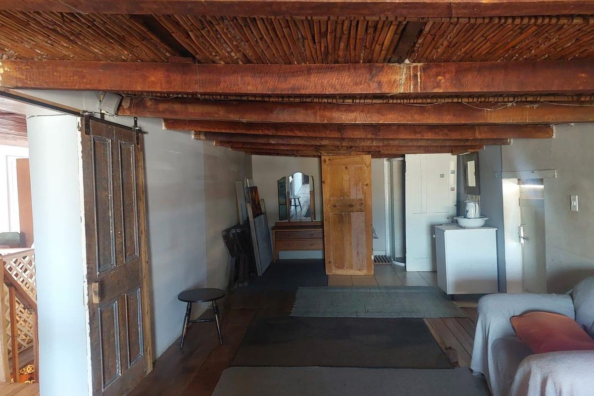 Rustic interior space featuring exposed timber beam ceiling, wooden flooring, and traditional barn-style sliding door, offering a character-filled living area.