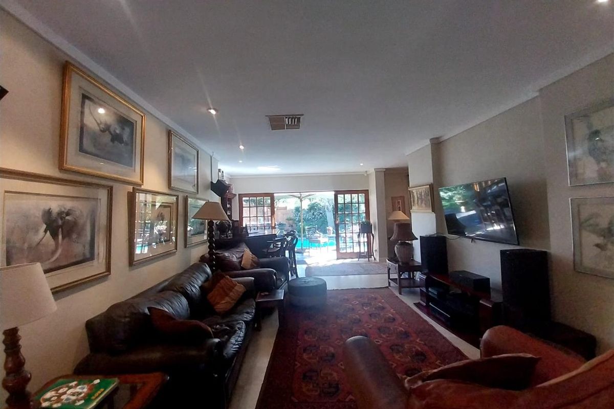 Spacious living room featuring recessed downlighting, tiled flooring, and double glass doors providing direct access to the outdoor pool area.