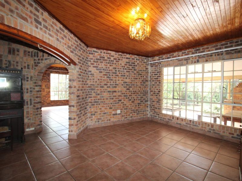 Spacious living area featuring rustic exposed brick walls, a warm timber ceiling, and large windows that provide ample natural light.