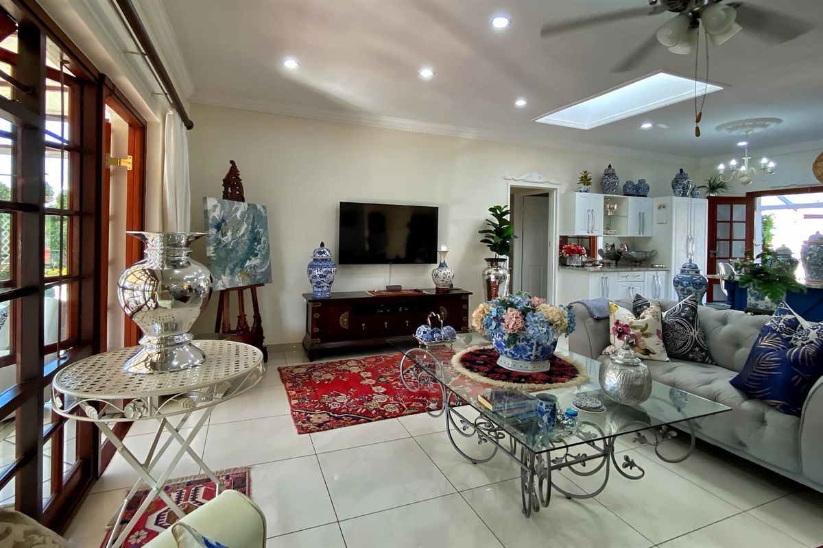 Spacious living room featuring tiled flooring, recessed lighting, a ceiling fan, and a skylight, with direct access to the patio through wooden french doors.