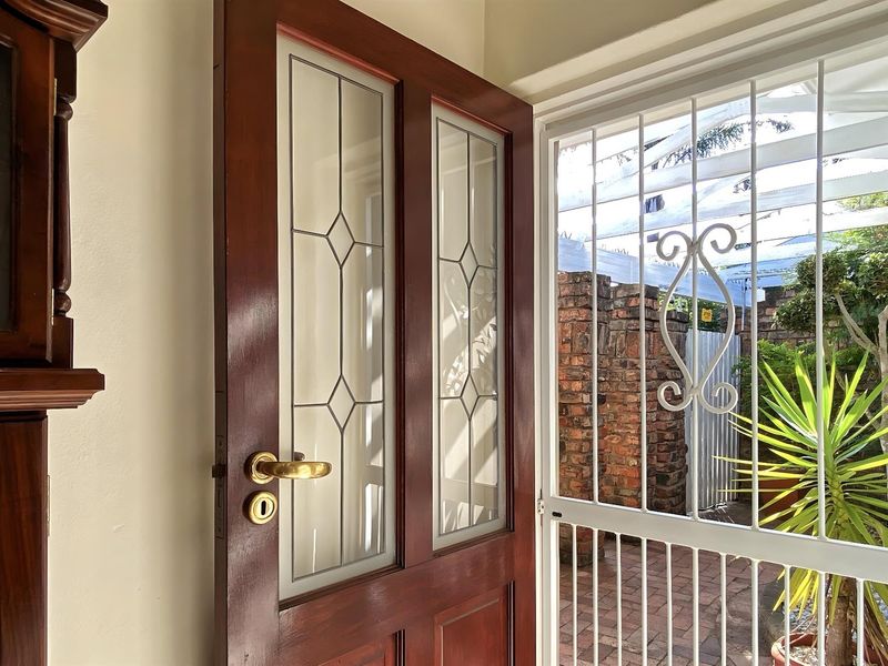 Entrance area featuring a solid timber front door with decorative leaded glass panels and a white security gate.