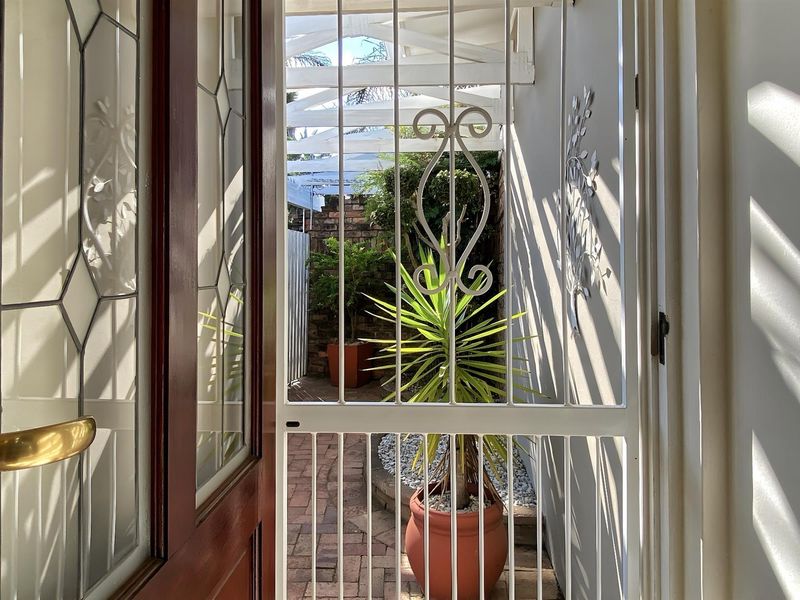 View from the entrance through a security gate to a paved outdoor courtyard area with a pergola.