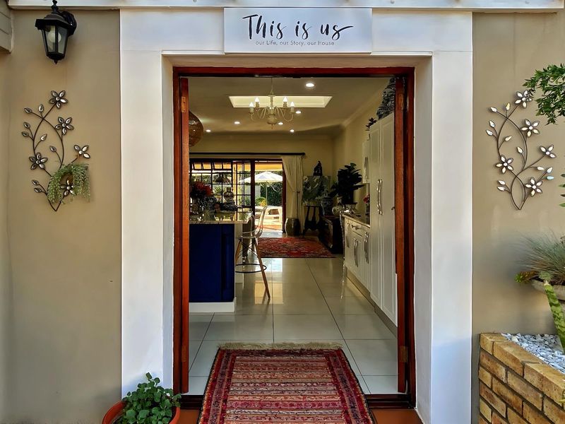 A welcoming entrance doorway featuring a timber frame, tiled flooring, and recessed lighting, providing a clear view into the open-plan living area.