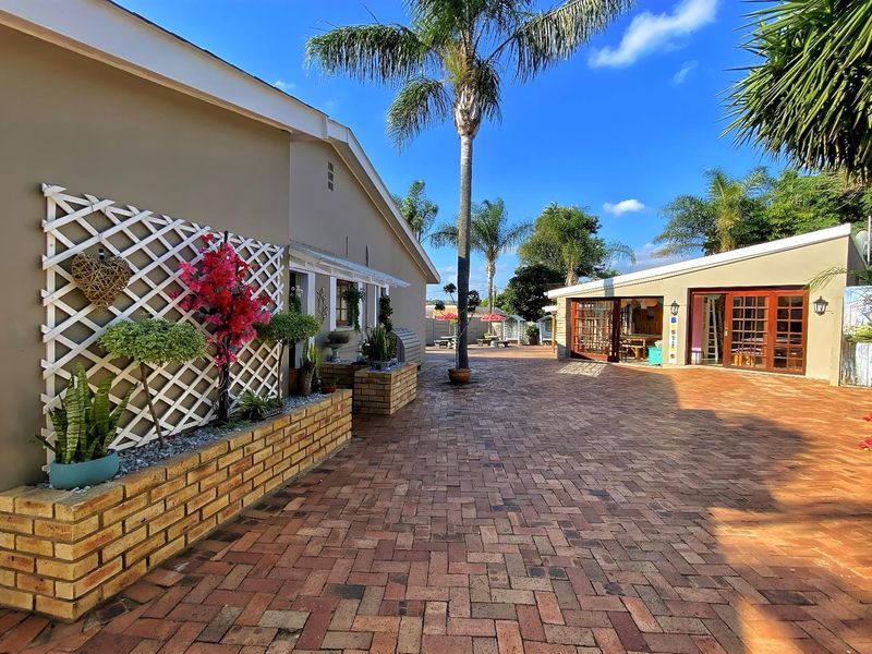Spacious paved rear courtyard area featuring a brick planter box, trellis, and access to the main dwelling through timber-framed glass doors.