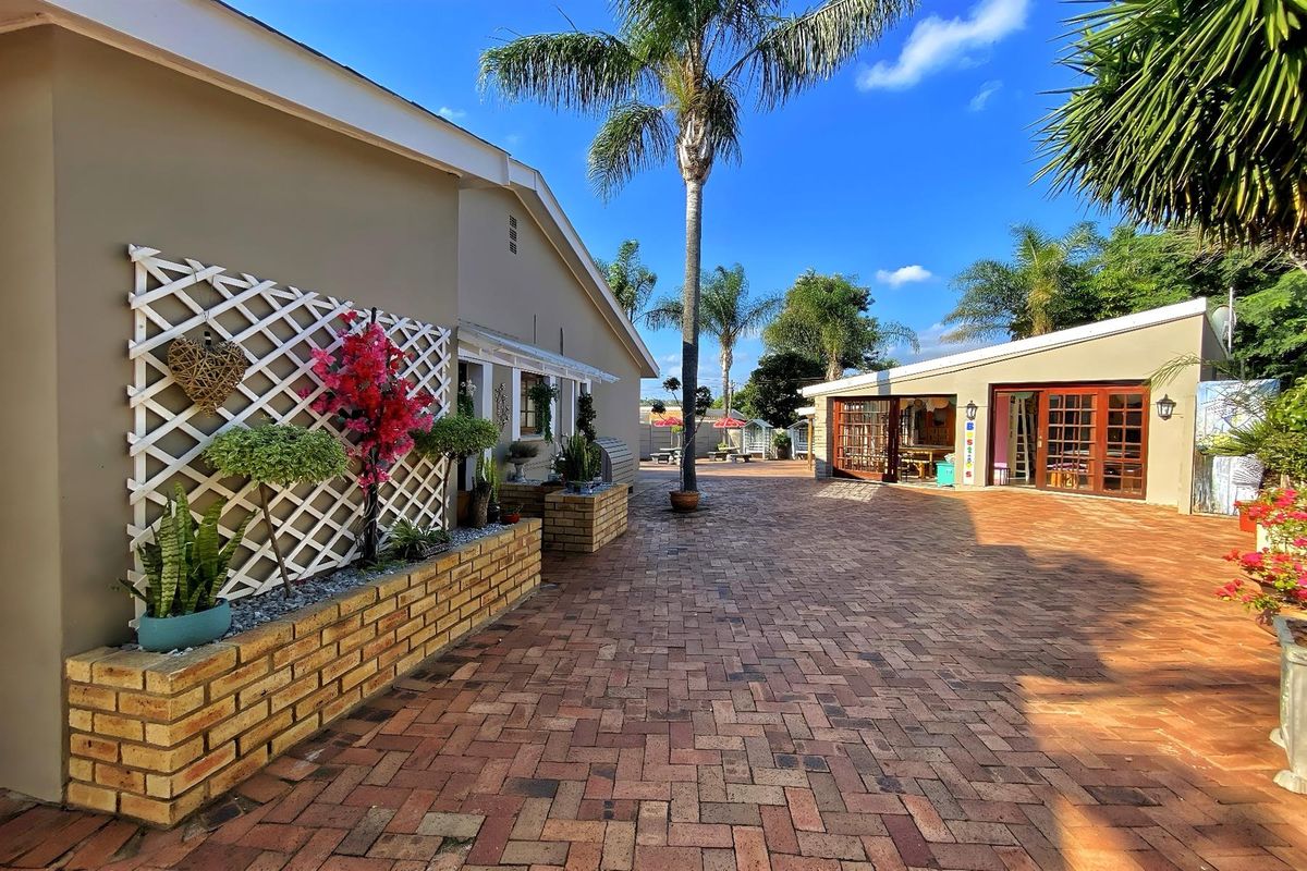Spacious paved rear courtyard area featuring a brick planter box, trellis, and access to the main dwelling through timber-framed glass doors.
