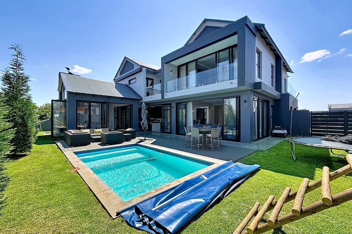 Modern double-story residence featuring a swimming pool, expansive timber decking, and seamless indoor-outdoor flow through large sliding glass doors.