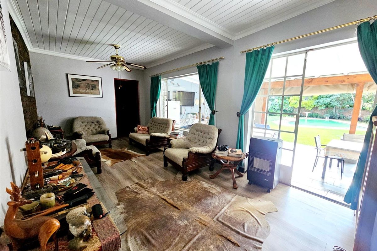 Spacious living room featuring wood-look flooring, a tongue-and-groove ceiling, and large glass doors providing direct access to the outdoor patio and pool area.