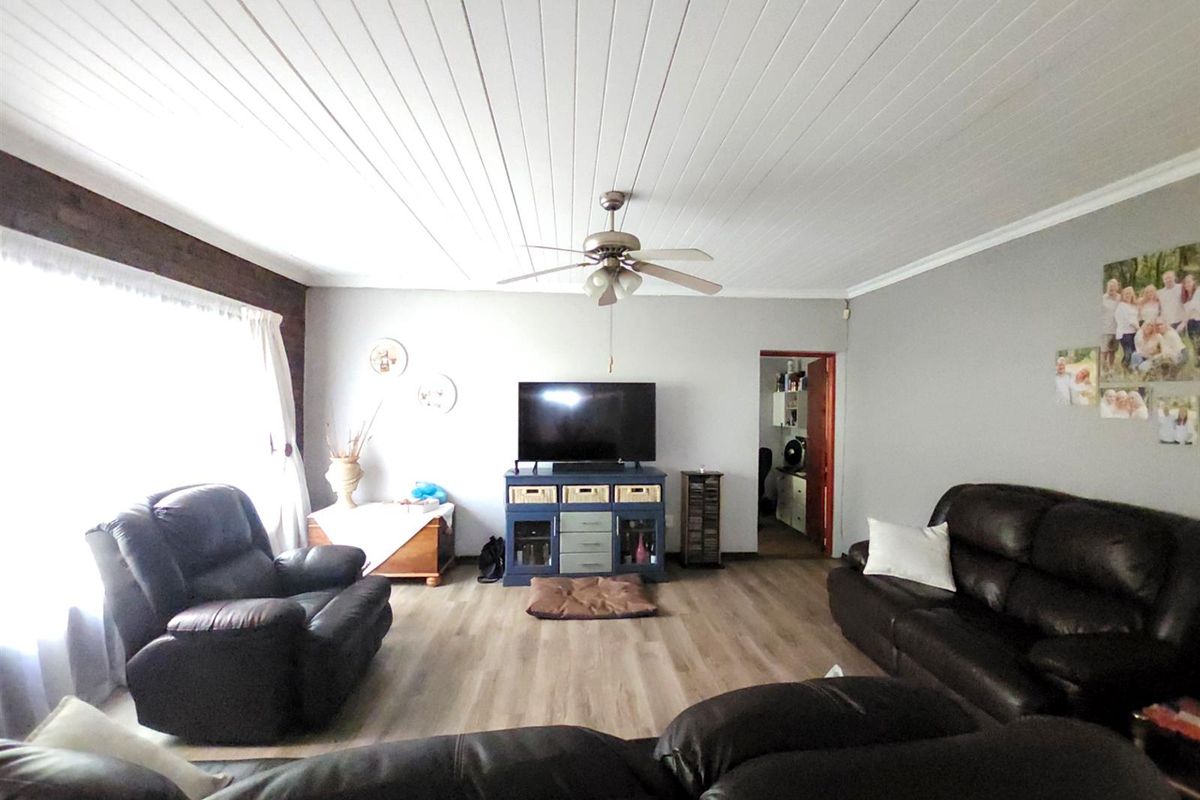 A comfortable living room featuring light wood-look flooring, a white tongue-and-groove ceiling, and a central ceiling fan.