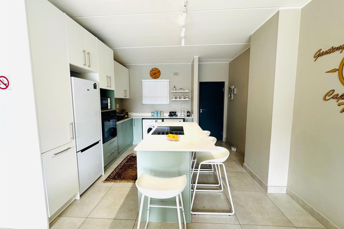 Modern kitchen featuring a central island with integrated cooktop, sleek cabinetry, tiled flooring, and built-in appliance spaces.
