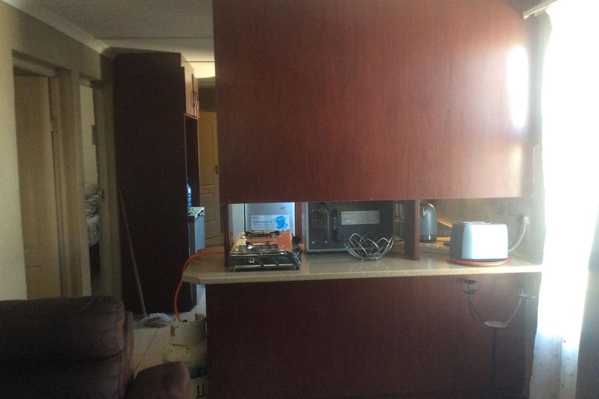 A compact kitchen area featuring built-in dark wood cabinetry and a functional countertop workspace.