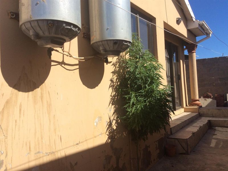 Rear exterior view of the property showing wall-mounted electric water heaters, a sliding door entrance, and tiled steps with visible wear to the exterior finish.