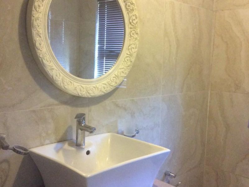 A modern bathroom featuring a vessel sink on a vanity cabinet with stone countertop and full-height wall tiling.