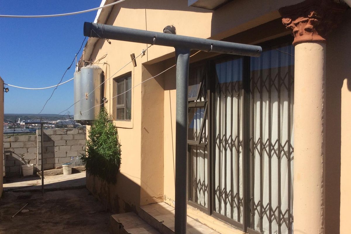 Rear exterior view of the property featuring a sliding door with security gate, external geyser, and concrete paved area.