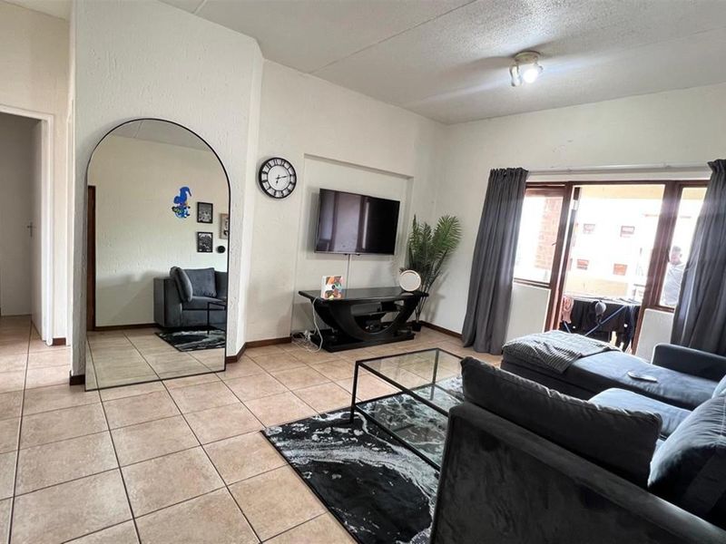 A living room featuring ceramic floor tiles and a sliding glass door providing access to an outdoor area.