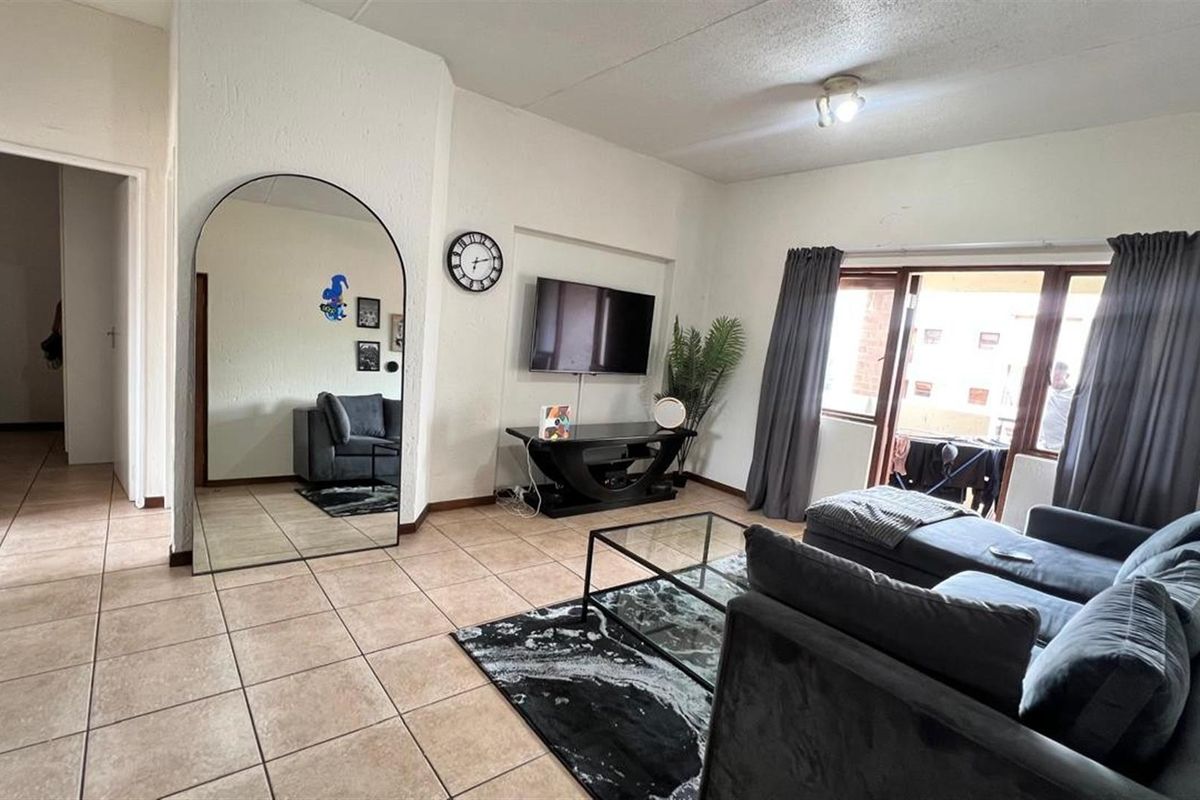 A living room featuring ceramic floor tiles and a sliding glass door providing access to an outdoor area.