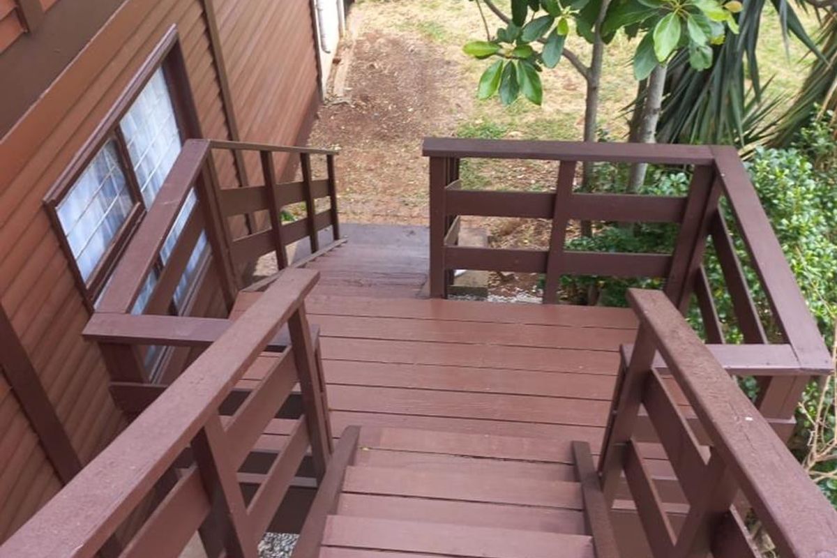 Exterior timber staircase leading from the upper level to the rear garden area, featuring wooden railings and siding.