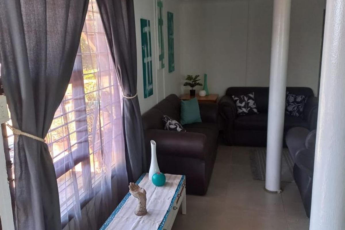 A living area featuring tiled flooring, a structural support column, and large windows with curtain treatments.