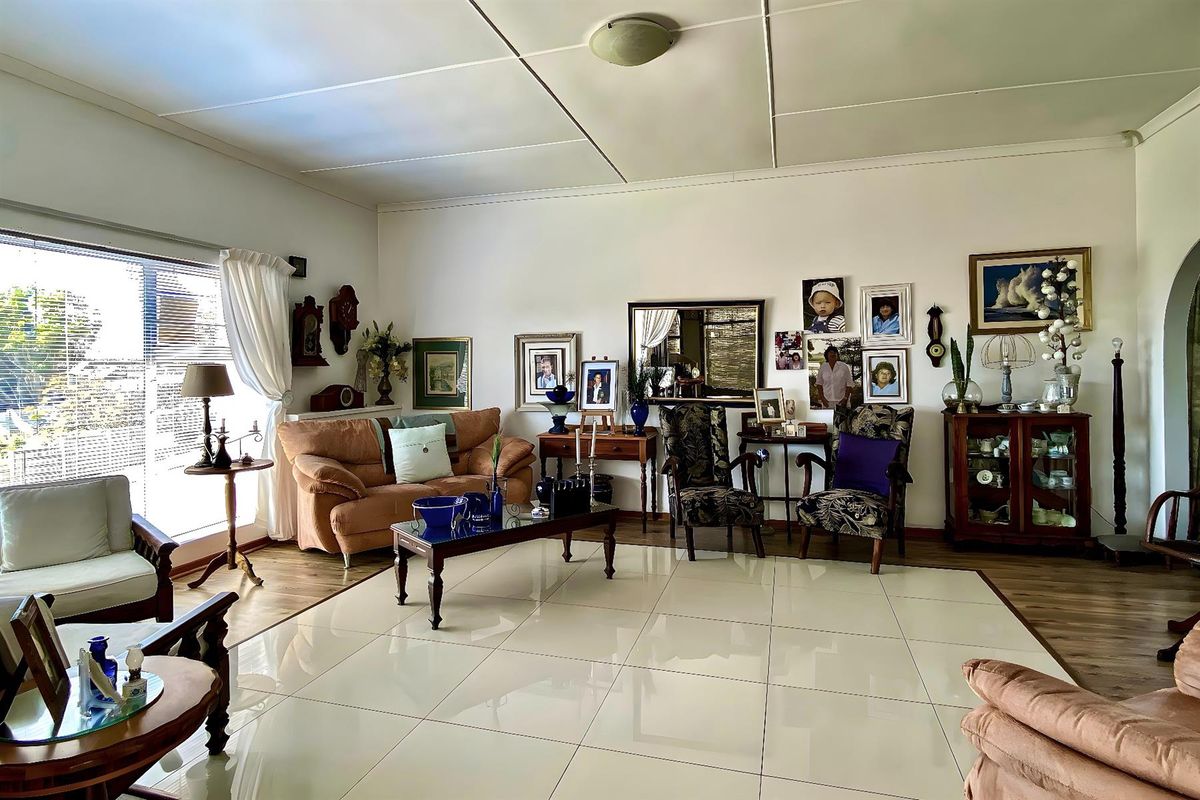 Spacious living room featuring large format floor tiles, neutral walls, and natural light through a large window.