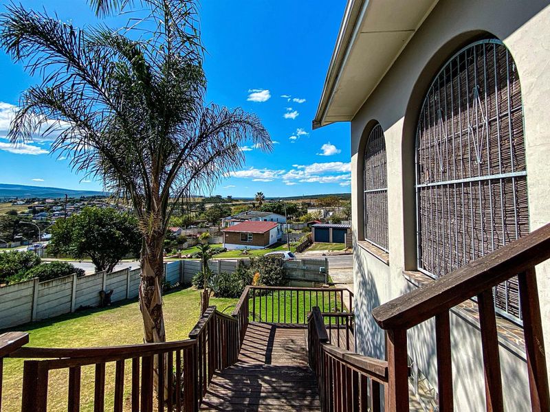 Elevated timber deck overlooking the rear garden and surrounding neighbourhood, featuring arched window detailing and secure metal security screens.