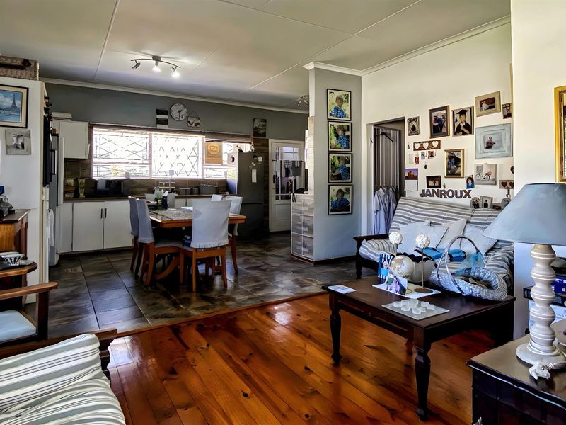 Open-plan living and dining area featuring polished wooden flooring, tiled kitchen zone, and neutral wall finishes.