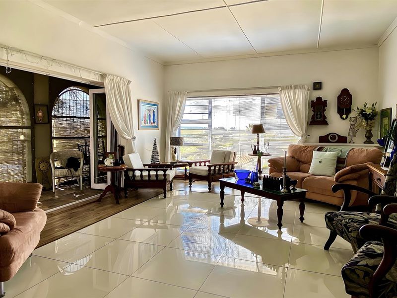 Spacious living room featuring large windows, polished floor tiles, and direct access to an outdoor patio area.